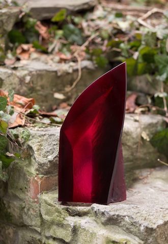 Červená skleněná trofej na kamenných schodech obklopená zelení