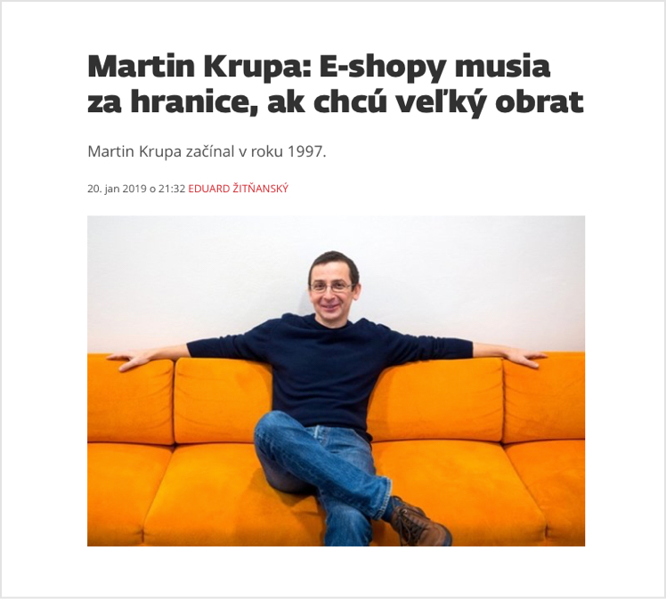 Muž sedící na oranžové pohovce s úsměvem na tváři