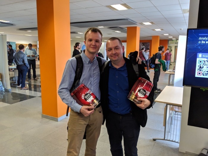 Dva muži drží pivní sudy na akci v interiéru s oranžovými sloupy