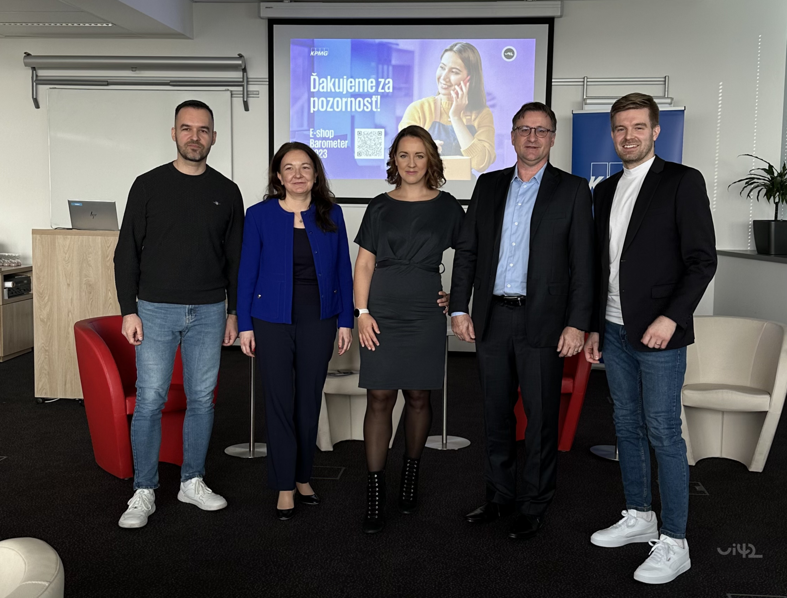 Skupina lidí stojí před obrazovkou s nápisem Děkujeme za pozornost. Na obrazovce je logo KPMG a text E-shop barometr 2023. V pozadí je projektor a kancelářské prostředí.