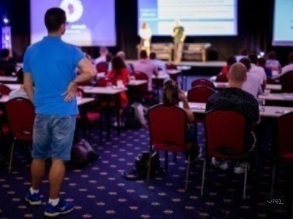 Lidé sedící na konferenci MastersGate s prezentací na pódiu