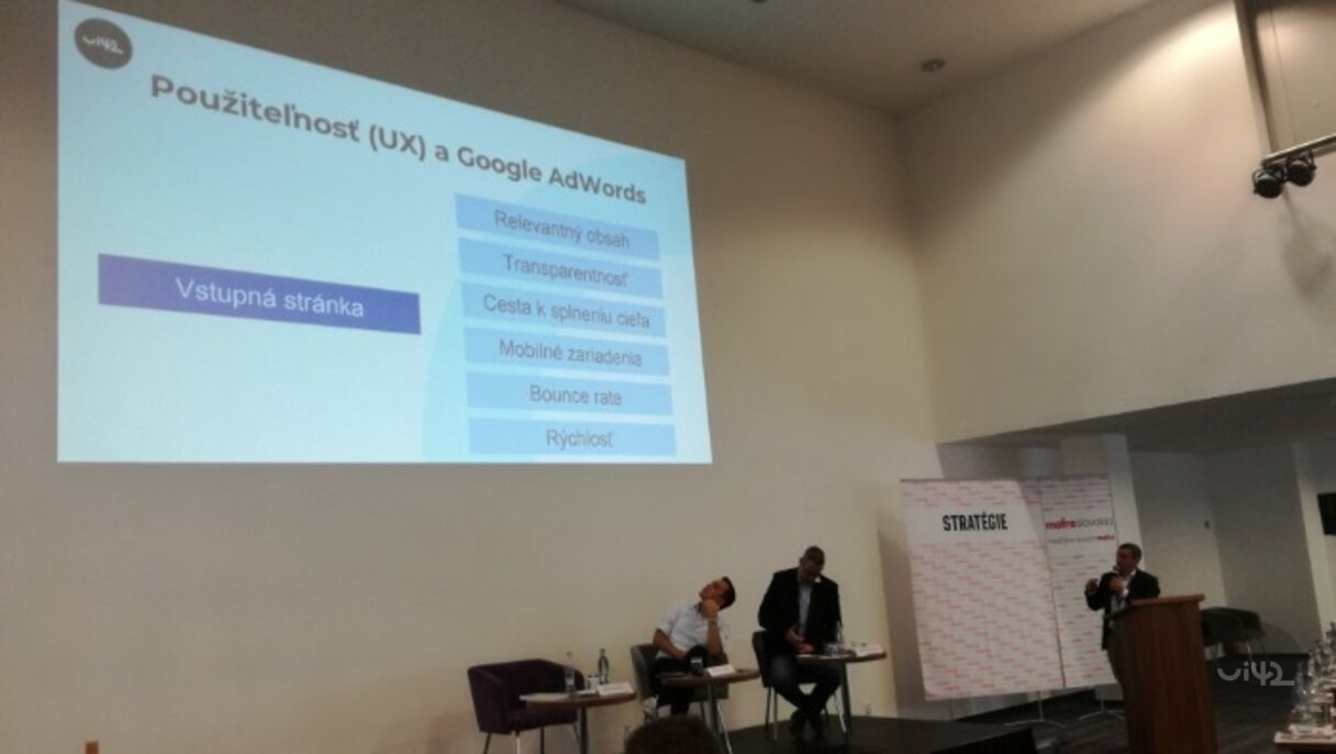 Prezentace na téma Použitelnost (UX) a Google AdWords na online summitu o výkonnostním marketingu. Na obrázku jsou přednášející a projekce s body jako Vstupní stránka, Relevantní obsah, Transparentnost.