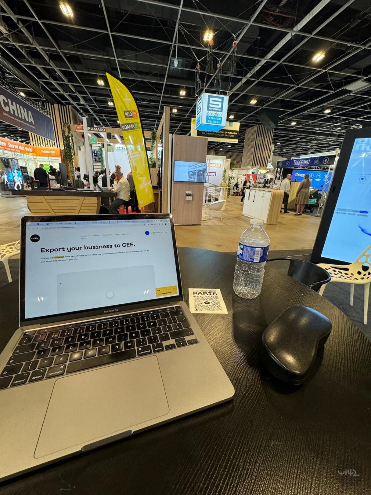 Notebook a láhev vody na stole na obchodní výstavě v Paříži