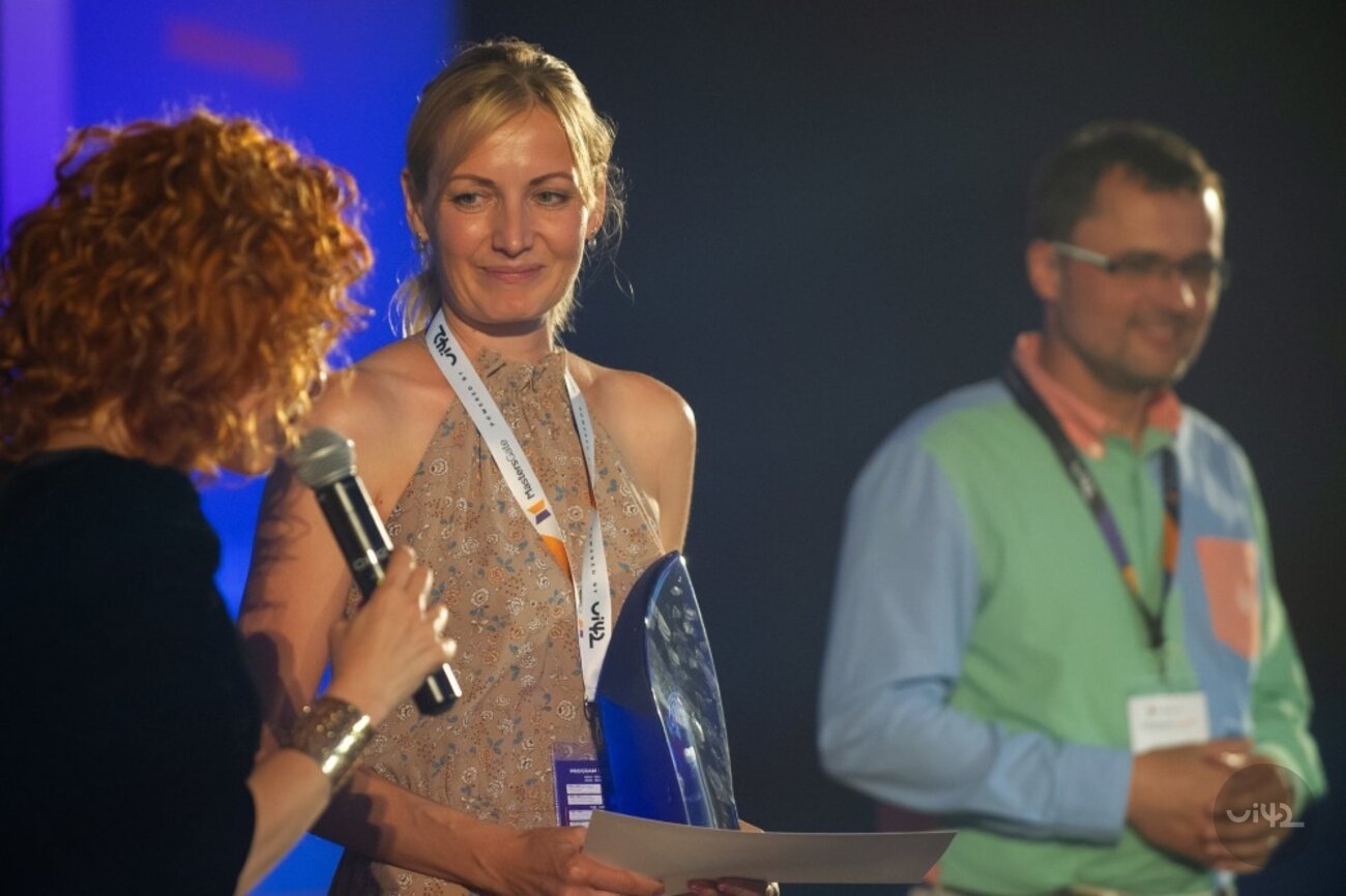 Žena přebírá ocenění na pódiu během akce MastersGate 2018.