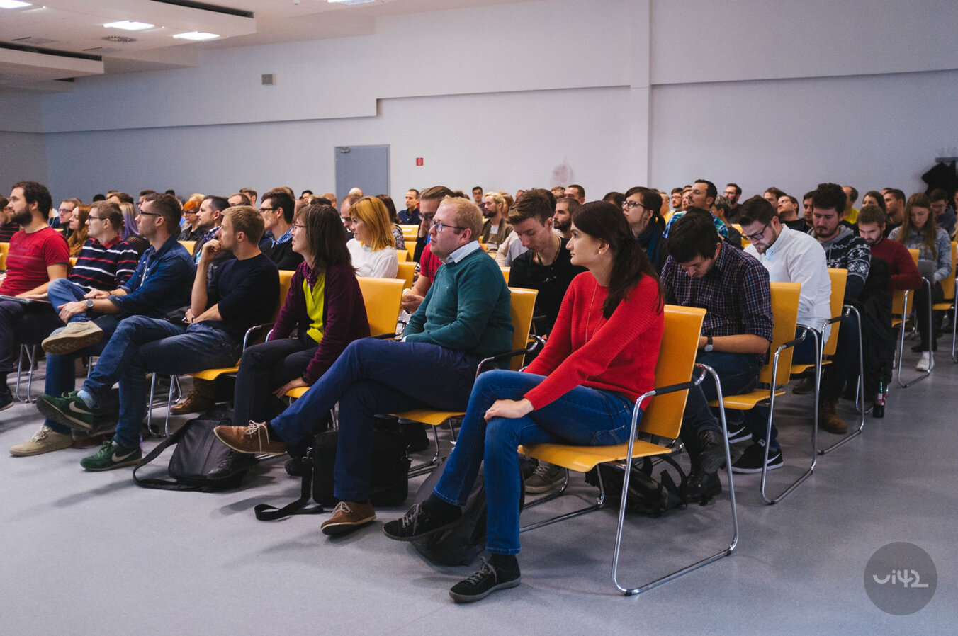 Účastníci konference World Usability Day 2017 sedí v řadě na židlích během prezentace.