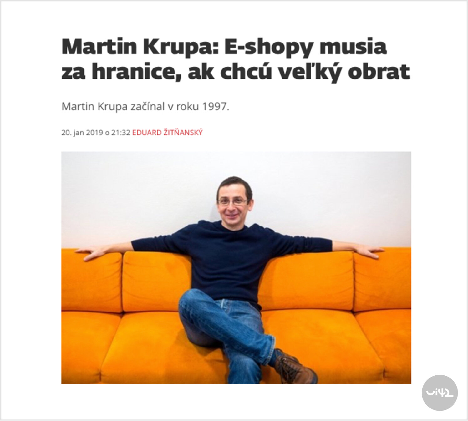 Muž sedící na oranžové pohovce s úsměvem na tváři